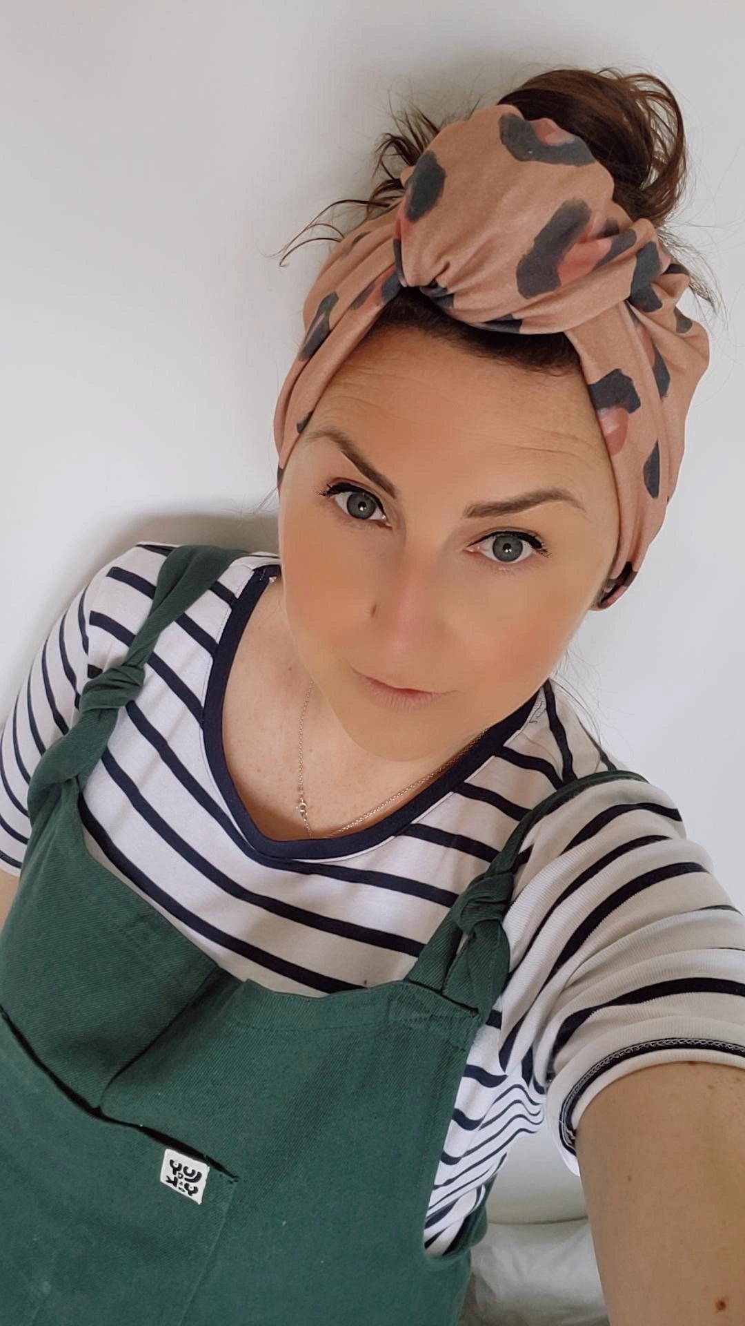 female wearing large headband with large knot on forehead in beige leopard print design